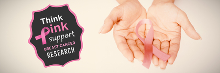 Breast cancer awareness message against two hands displaying pink ribbon for breast cancer awarenessの写真素材