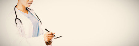 Serious female doctor writing on a note pad on a white bakgroundの写真素材