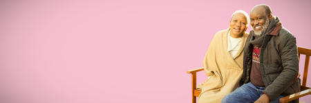 Peaceful senior couple sitting on a bench against pink backgroundの写真素材