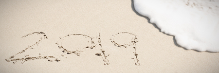 2019 written in the sand with waves coming in