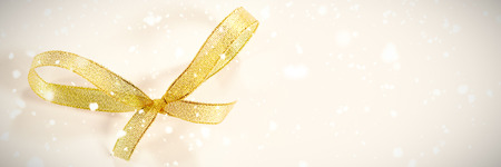 Snow falling against decoration golden bow tieの写真素材