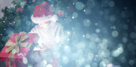 Child opening his christmas present against blue abstract light spot designの写真素材