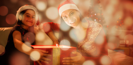 Festive mother and daughter opening a glowing christmas gift against light circles on black...