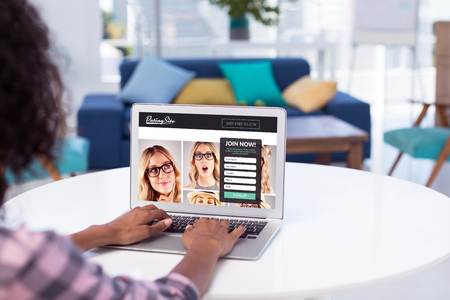 Female executive working on laptop at desk against subscription form on dating siteの写真素材
