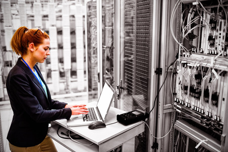 Technician using laptop while analyzing server in server roomの写真素材
