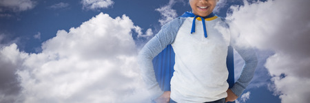 Boy pretending to be superhero against sky and cloud on a sunny dayの写真素材