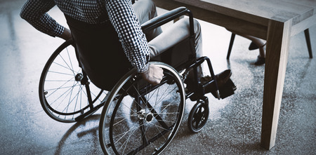 Handicapped executive sitting on wheelchair at desk in officeの写真素材