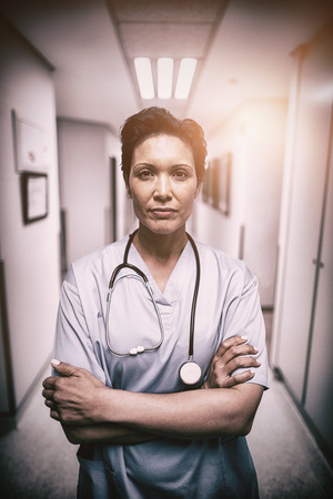 Portrait of female nurse standing with arms crossed in corridor of hospitalの写真素材