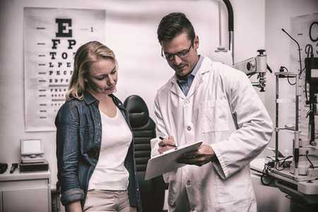 Optometrist discussing eye test report with female patient in ophthalmology clinicの写真素材