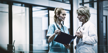 Female doctor and nurse discussing over a medical report in hospital