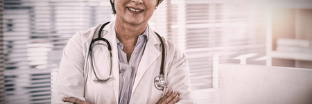 Portrait of a smiling female doctor standing with arms crossed at medical officeの写真素材