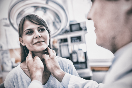 Doctor examining a female patients neck in the hospitalの写真素材