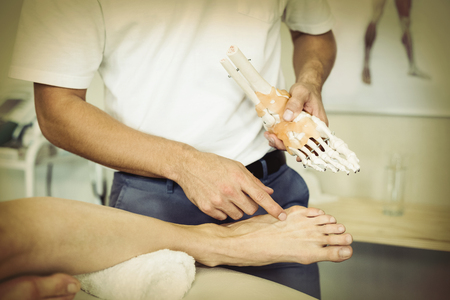 Physiotherapist explaining feet model to patient in clinicの写真素材