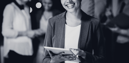 Portrait of happy businesswoman using digital tablet in office at nightの写真素材