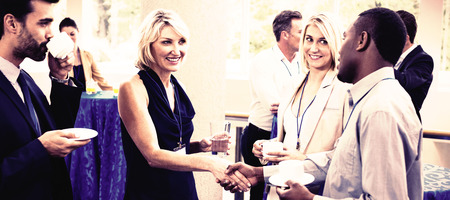 Business executives interacting with each other while having coffee at conference centerの写真素材