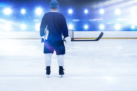 Ice hockey player on the ice against composite image of blue spotlightの写真素材