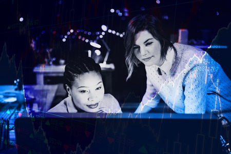 Stocks and shares against women looking at computerの写真素材