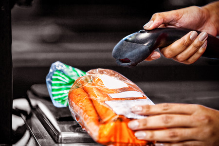 Close-up of woman scanning goods at checkout counter in supermarket