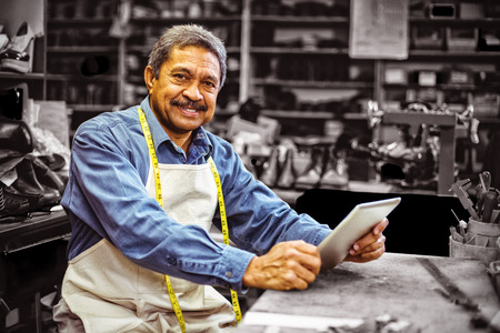 Portrait of shoemaker using digital tablet in workshop