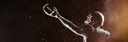 Digitally generated image of powder against american football player in helmet holding rugby ballの写真素材