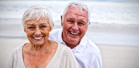 Portrait of smiling senior couple standing on the beachの写真素材