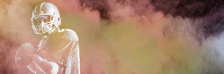 Splashing of powder against american football player holding rugby ballの写真素材