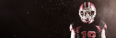 Digitally generated image of powder against american football player standing with rugby helmetの写真素材