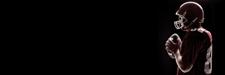 Side view of American football player standing with rugby helmet and ballの写真素材