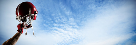 American football player cheering with hand raised against view of cloudy skyの写真素材