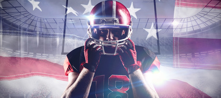 American football player standing with rugby helmet against close-up of an american flagの写真素材