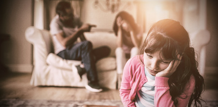 Sad girl listening to her parents arguing at homeの写真素材