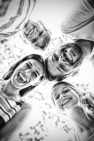 Smiling family forming huddle against skyの写真素材