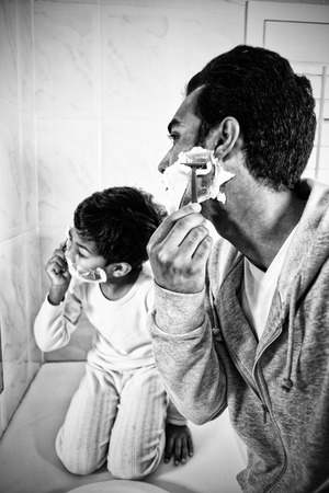 Father and son shaving together in the bathroom at homeの写真素材