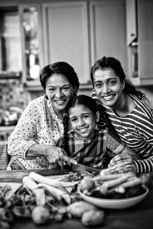 Portrait of smiling multi-generation family preparing food together in kitchen at homeの写真素材