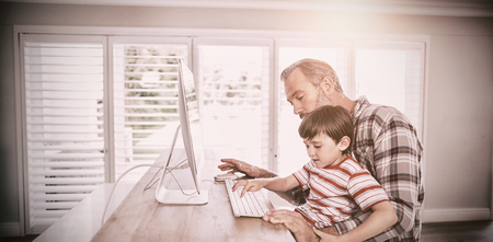 Father and son working on computer at homeの写真素材