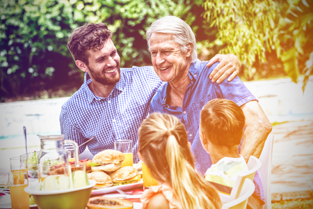 Happy father and son with children at dinning table in lawnの写真素材