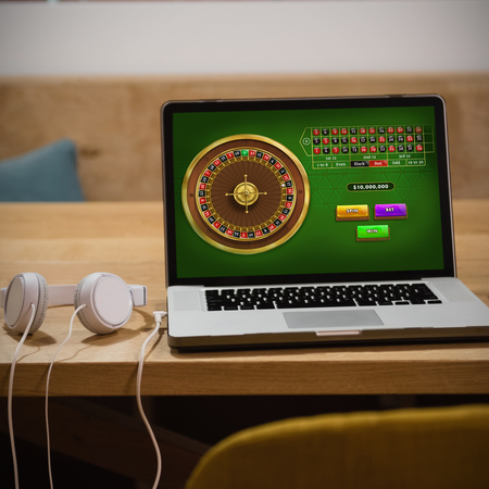 Online Roulette Game  against laptop with headphones and cup on tableの写真素材