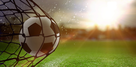 Football hitting the back of the net against close-up of soccer fieldの写真素材
