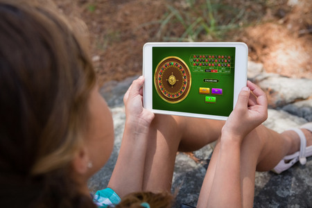 Online Roulette Game  against girl holding digital tablet in the forestの写真素材