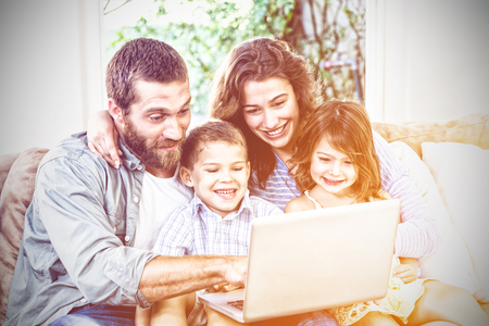 Smiling family with laptop sitting on sofaの写真素材
