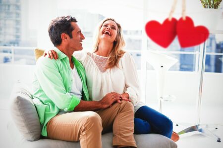 Hearts hanging on a line against couple relaxing on sofa at home