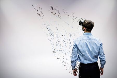 Man holding virtual reality glasses against grey backgroundの写真素材