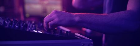 Mid section of male dj mixing music on mixing console in bar
