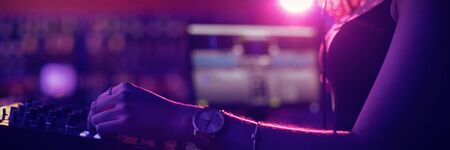 Female dj mixing music on mixing console in barの写真素材