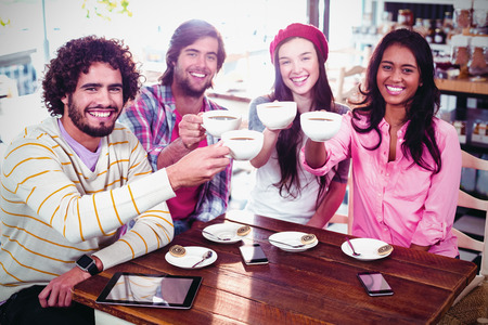 Group of happy friends holding cup of coffee in cafeの写真素材