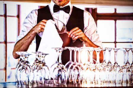 Mid section of bartender cleaning wine glass at bar counterの写真素材