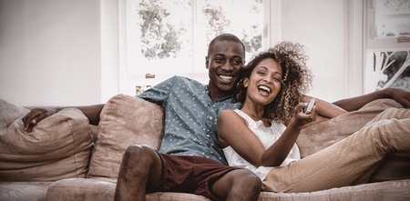 Young couple watching television while relaxing on the sofaの写真素材