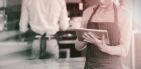 Waitress using digital tablet at counter in cafÃÂ©の写真素材