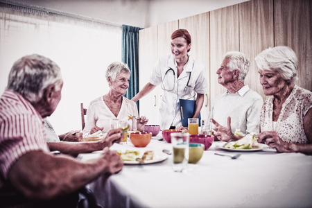 Pensioners at lunch with nurse in the retirement houseの写真素材
