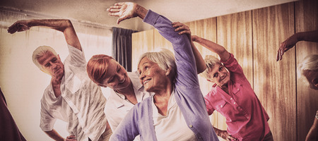 Group of seniors doing exercises with nurse in retirement houseの写真素材